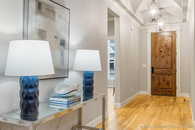 entrance foyer featuring light wood-style floors, crown molding, baseboards, and an inviting chandelier