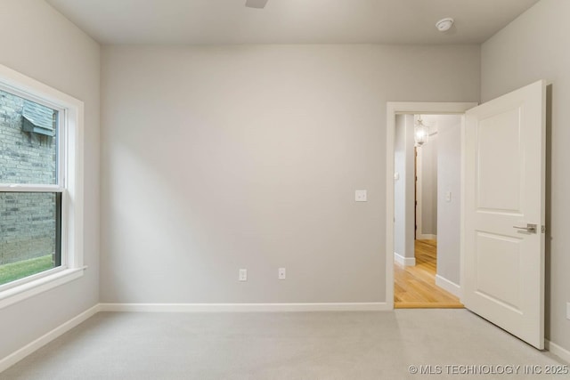 unfurnished room with light colored carpet and baseboards