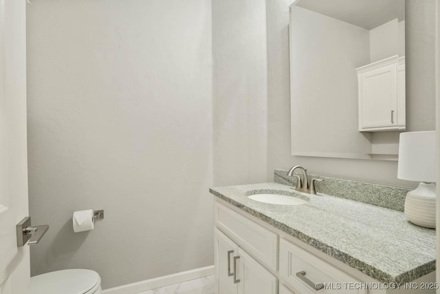 bathroom with marble finish floor, toilet, vanity, and baseboards