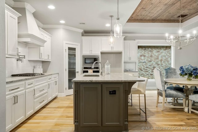 kitchen with white cabinets, light wood-type flooring, premium range hood, and stainless steel appliances