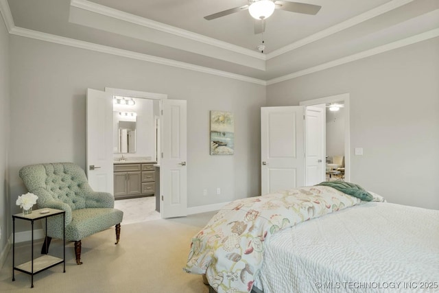 bedroom featuring baseboards, light colored carpet, ensuite bath, a tray ceiling, and crown molding