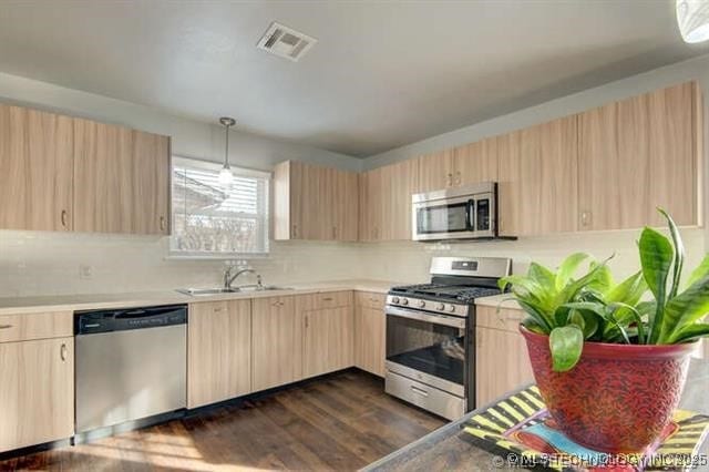 kitchen featuring light brown cabinetry, sink, decorative light fixtures, appliances with stainless steel finishes, and dark hardwood / wood-style floors