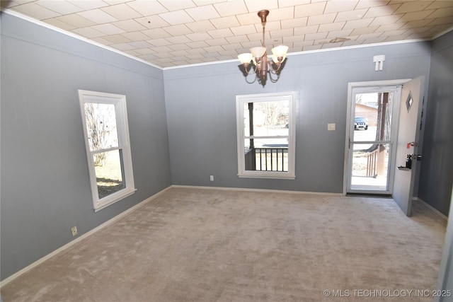 carpeted spare room with crown molding, a healthy amount of sunlight, and an inviting chandelier