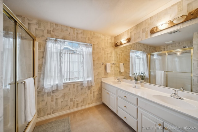 bathroom with vanity, a shower with door, and a healthy amount of sunlight