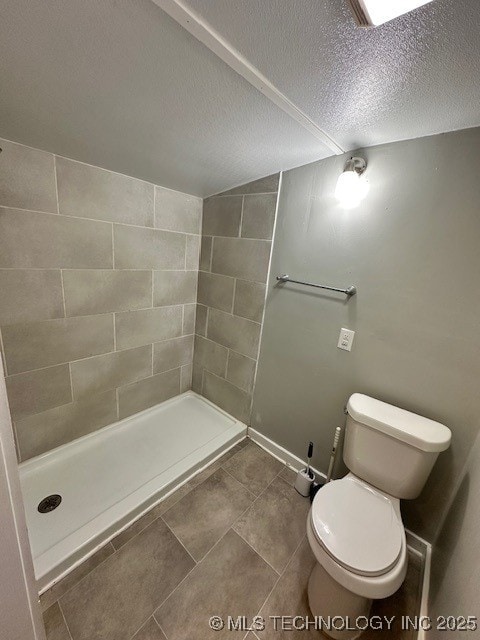 bathroom with a tile shower, a textured ceiling, and toilet