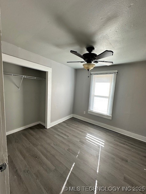 unfurnished bedroom with dark wood-type flooring, ceiling fan, a closet, and a textured ceiling