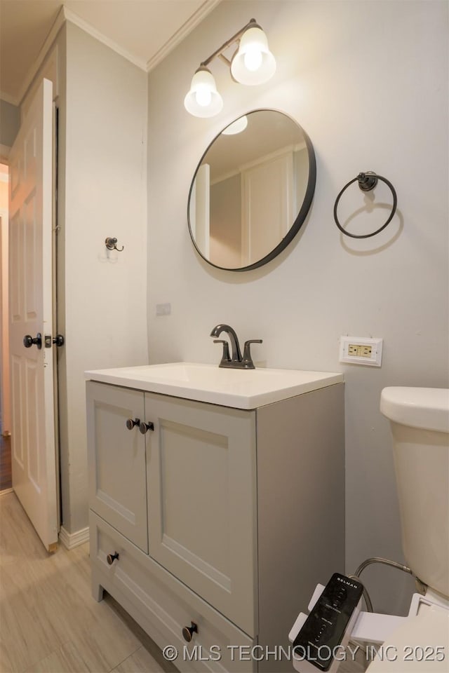 bathroom featuring hardwood / wood-style flooring, vanity, ornamental molding, and toilet