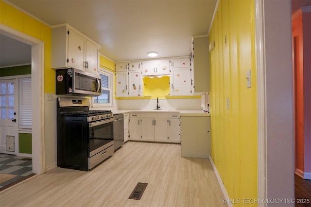 kitchen featuring backsplash, stainless steel appliances, white cabinets, and light wood-type flooring