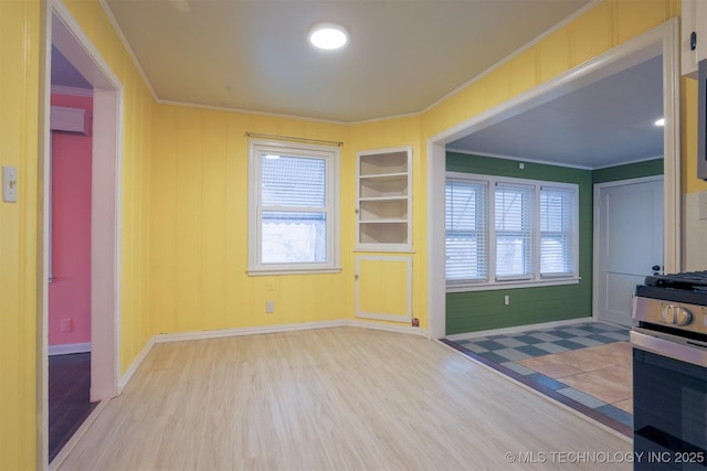 unfurnished living room featuring crown molding, light wood-type flooring, and built in shelves