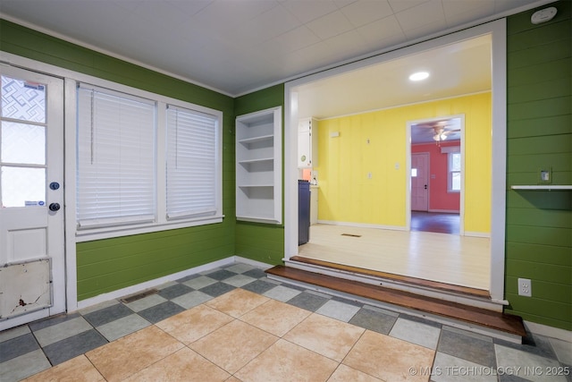 foyer entrance with ceiling fan and wood walls