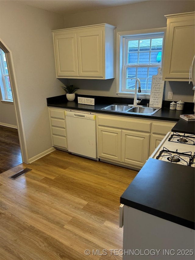 kitchen featuring dishwasher, sink, light hardwood / wood-style flooring, and white cabinets