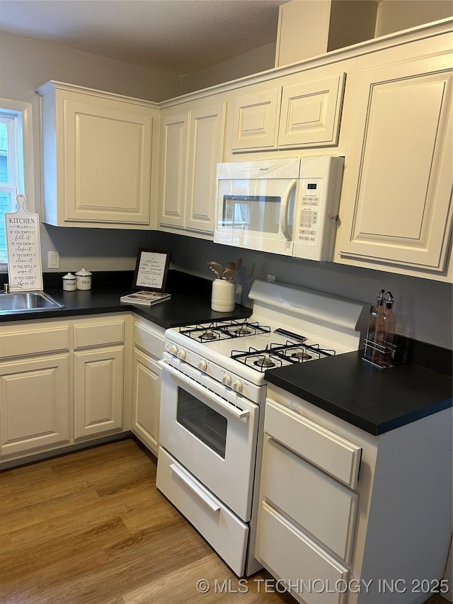 kitchen featuring white cabinetry, sink, white appliances, and light hardwood / wood-style flooring