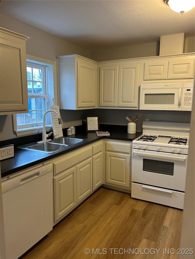 kitchen featuring white cabinetry, sink, white appliances, light hardwood / wood-style floors, and a textured ceiling