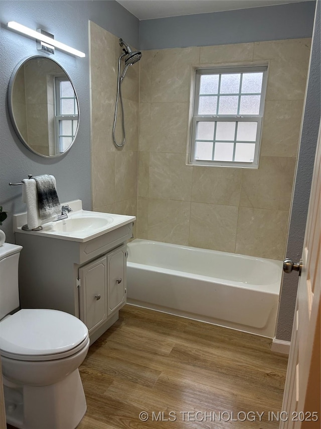 full bathroom featuring hardwood / wood-style flooring, vanity, toilet, and tiled shower / bath combo