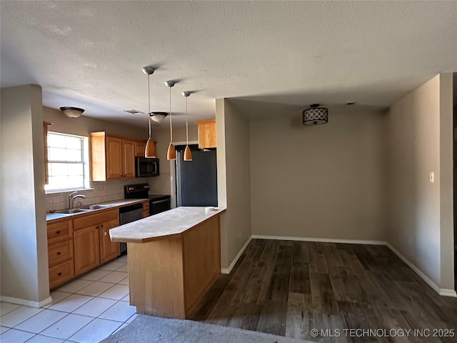 kitchen featuring decorative light fixtures, black appliances, sink, decorative backsplash, and kitchen peninsula