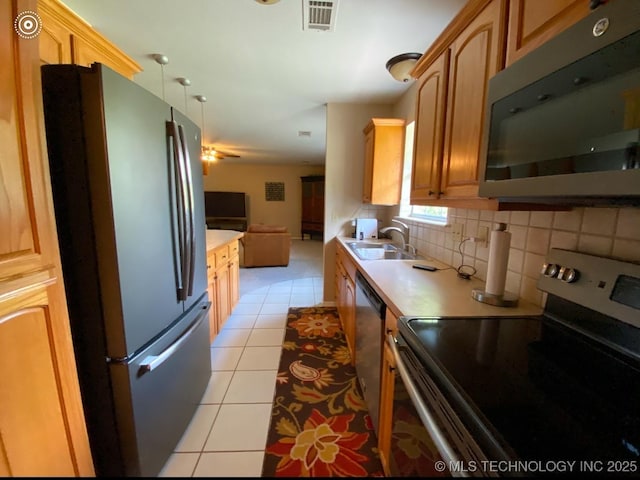 kitchen with appliances with stainless steel finishes, sink, light tile patterned floors, and backsplash