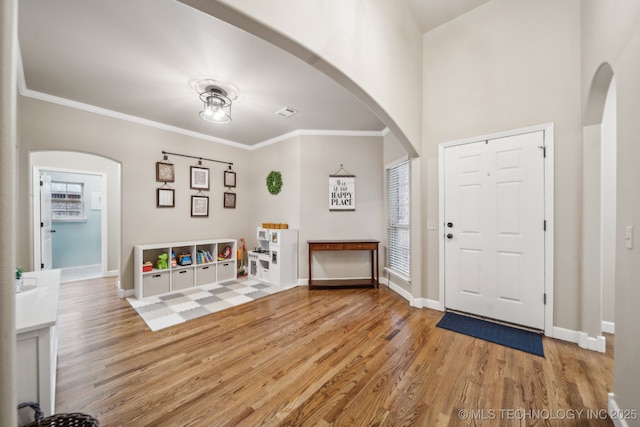 foyer with hardwood / wood-style floors and crown molding