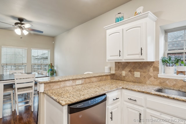 kitchen featuring white cabinetry, sink, stainless steel dishwasher, and light stone counters