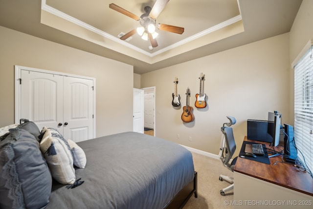 carpeted bedroom with ornamental molding, a tray ceiling, and a closet