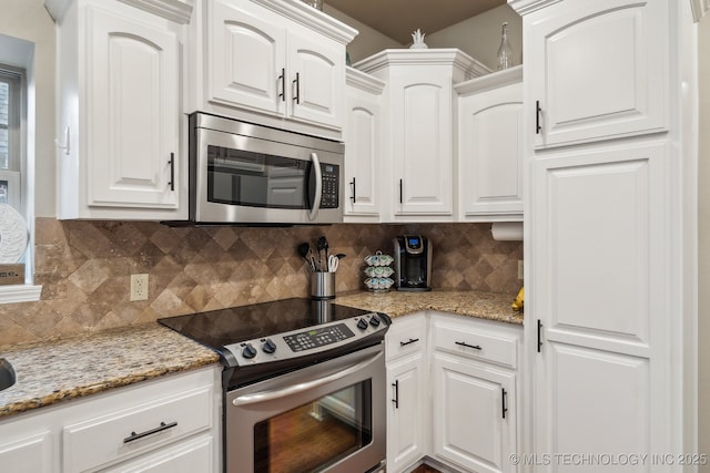 kitchen featuring light stone counters, backsplash, white cabinets, and appliances with stainless steel finishes