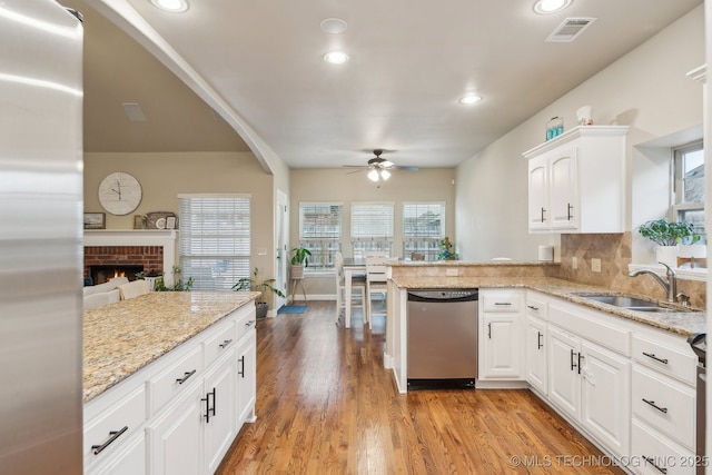 kitchen featuring sink, white cabinetry, light hardwood / wood-style flooring, stainless steel appliances, and light stone countertops