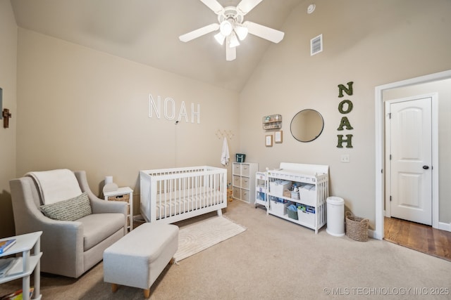 carpeted bedroom featuring high vaulted ceiling, a nursery area, and ceiling fan