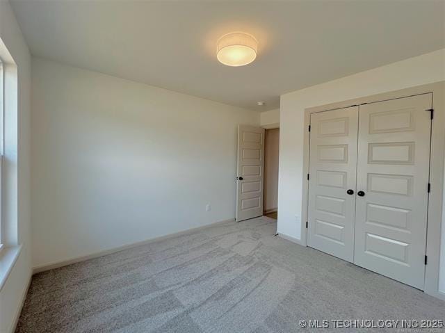 unfurnished bedroom with light carpet and a closet