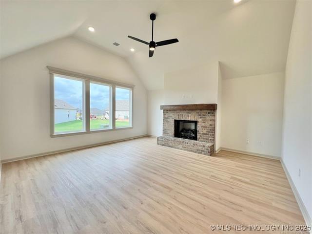 unfurnished living room featuring a brick fireplace, light hardwood / wood-style flooring, ceiling fan, and vaulted ceiling