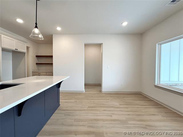 kitchen featuring decorative light fixtures, a kitchen breakfast bar, light wood-type flooring, and white cabinets