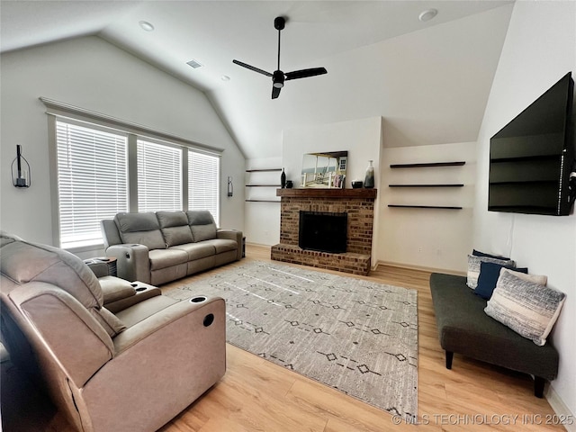 living room featuring light hardwood / wood-style flooring, a fireplace, ceiling fan, and vaulted ceiling