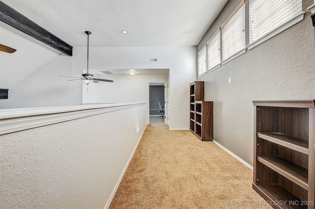 hallway with vaulted ceiling with beams, light colored carpet, and a textured ceiling