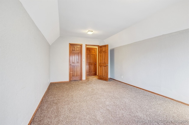 unfurnished bedroom featuring lofted ceiling and carpet floors