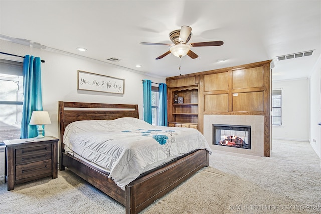 bedroom with light carpet, ornamental molding, ceiling fan, and a multi sided fireplace