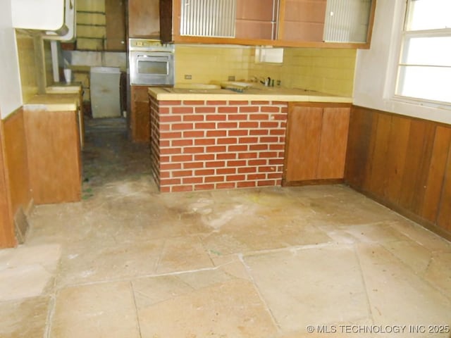 kitchen with oven, decorative backsplash, and wood walls