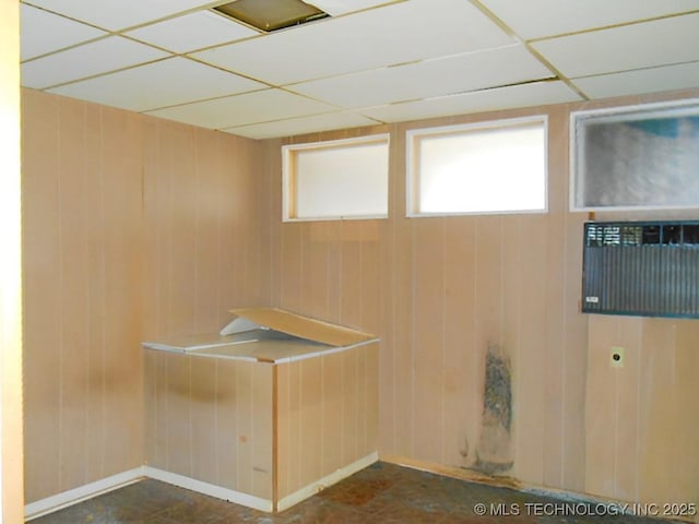 unfurnished room featuring a paneled ceiling and wooden walls