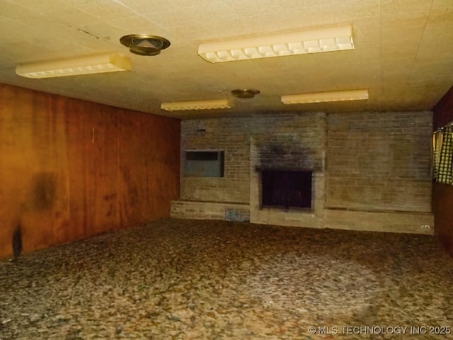 unfurnished living room with a brick fireplace and wooden walls