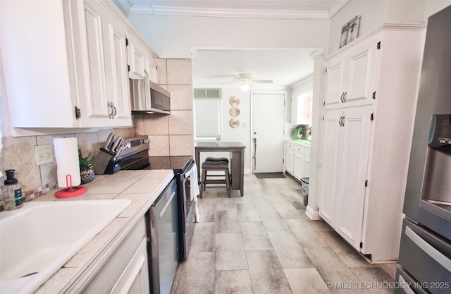 kitchen with white cabinetry, appliances with stainless steel finishes, sink, and tile countertops