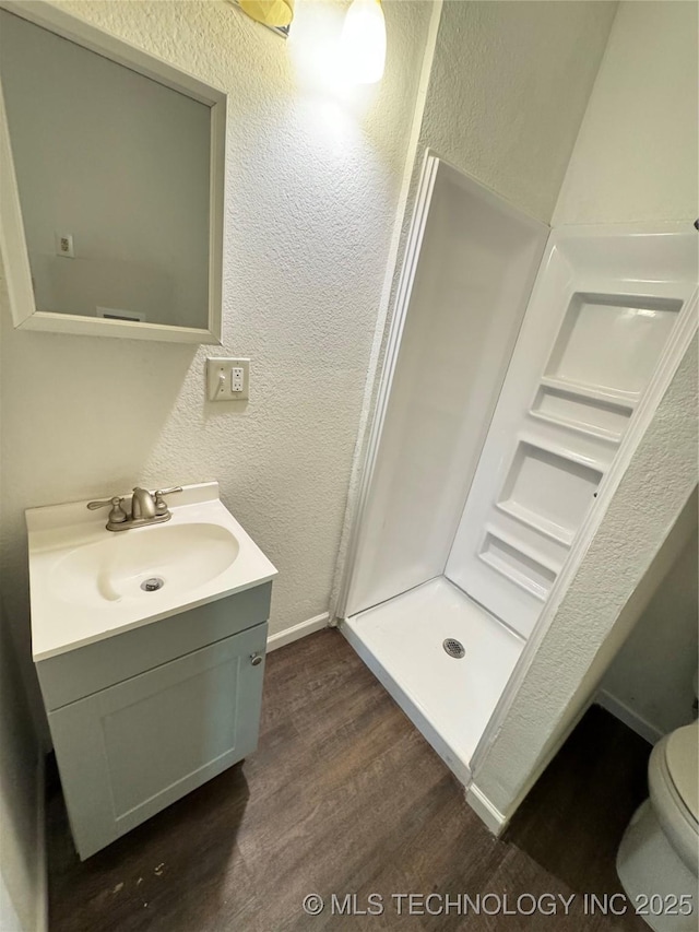 bathroom with vanity, hardwood / wood-style floors, walk in shower, and toilet