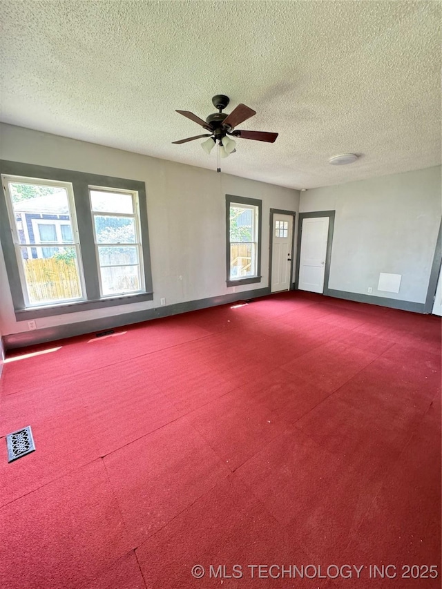 carpeted empty room with ceiling fan and a textured ceiling