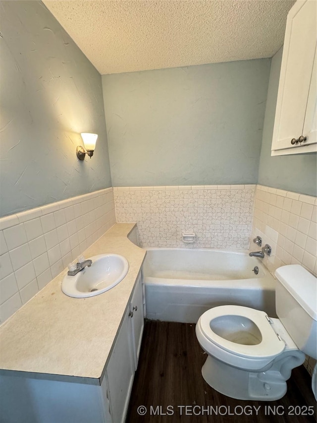 bathroom with a tub, hardwood / wood-style floors, a textured ceiling, and toilet