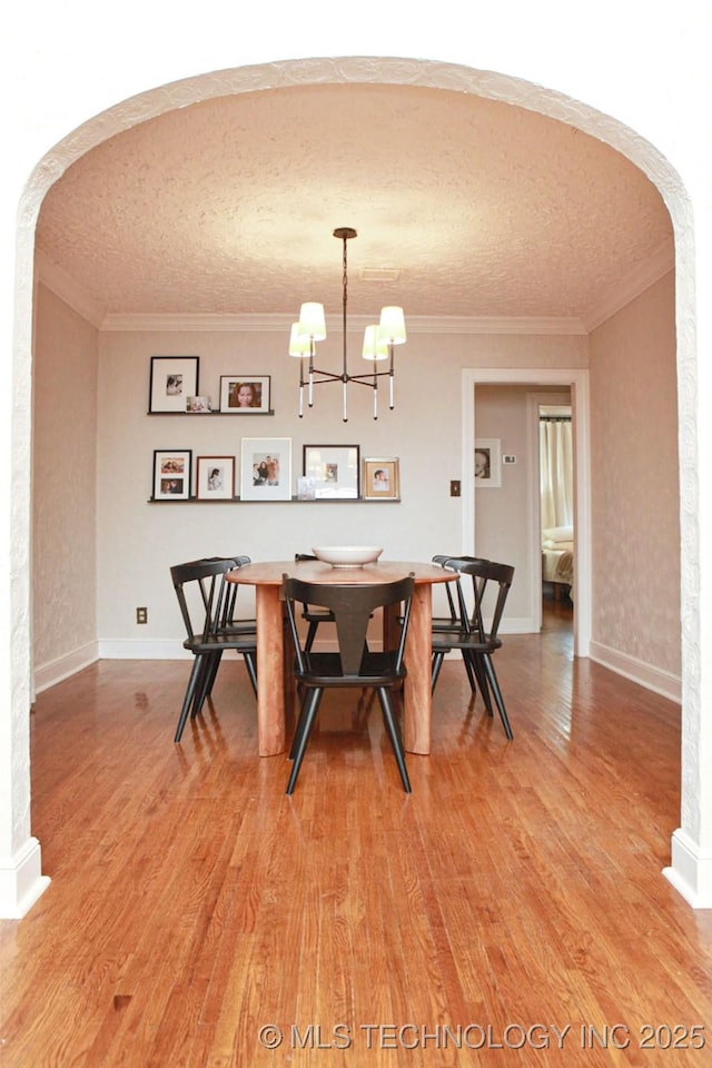 dining area with crown molding, a chandelier, and hardwood / wood-style flooring