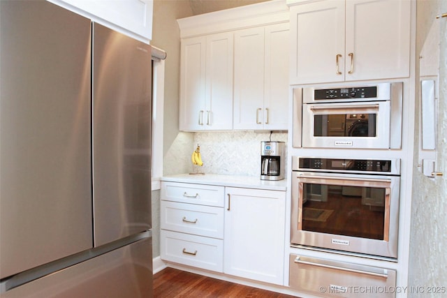 kitchen with stainless steel appliances, backsplash, white cabinets, and dark hardwood / wood-style flooring