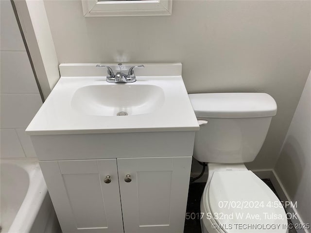 bathroom with vanity, a bath, and toilet