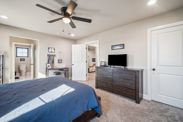 bedroom with connected bathroom, light colored carpet, and ceiling fan