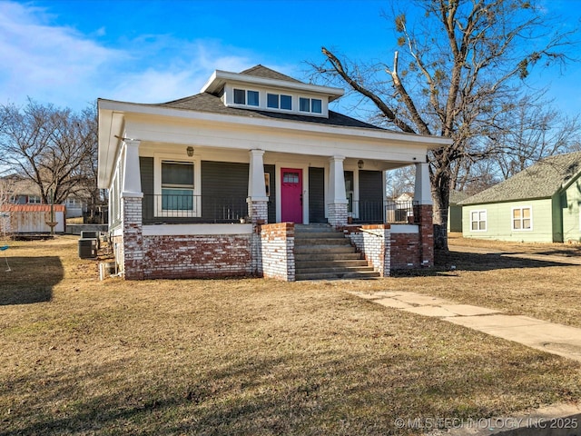 view of front facade featuring central AC unit, covered porch, and a front yard