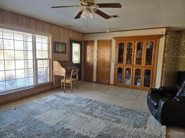 sitting room featuring light carpet, wooden walls, a textured ceiling, and plenty of natural light