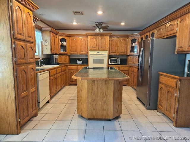 kitchen with light tile patterned floors, white appliances, sink, and a kitchen island