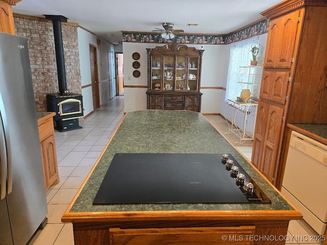 interior space featuring ceiling fan, light tile patterned floors, and a wood stove