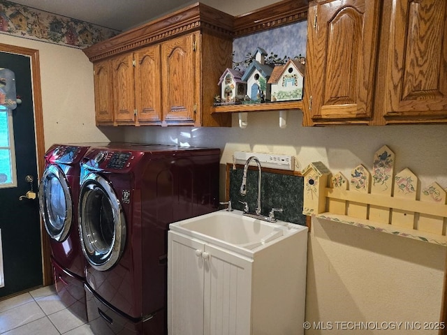 clothes washing area featuring cabinets, washing machine and clothes dryer, and light tile patterned flooring