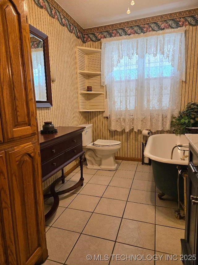 bathroom with tile patterned flooring, toilet, and a tub to relax in